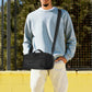 Black compact messenger bag worn crossbody with adjustable strap