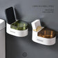 Two wall-mounted stainless ashtrays with lids, white bases with green and bronze cups