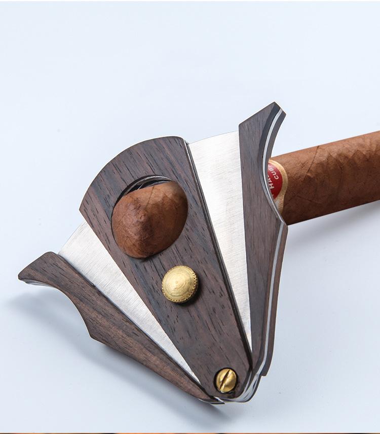 Cigar scissors cutting a cigar with dark wood handles and stainless blade