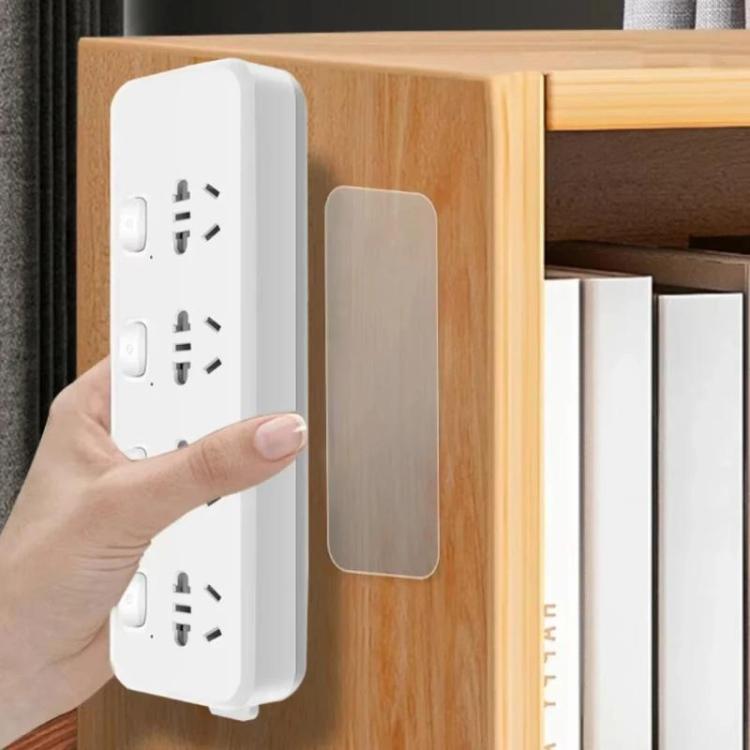 Hand pressing a clear double-sided adhesive pad onto an outlet cover