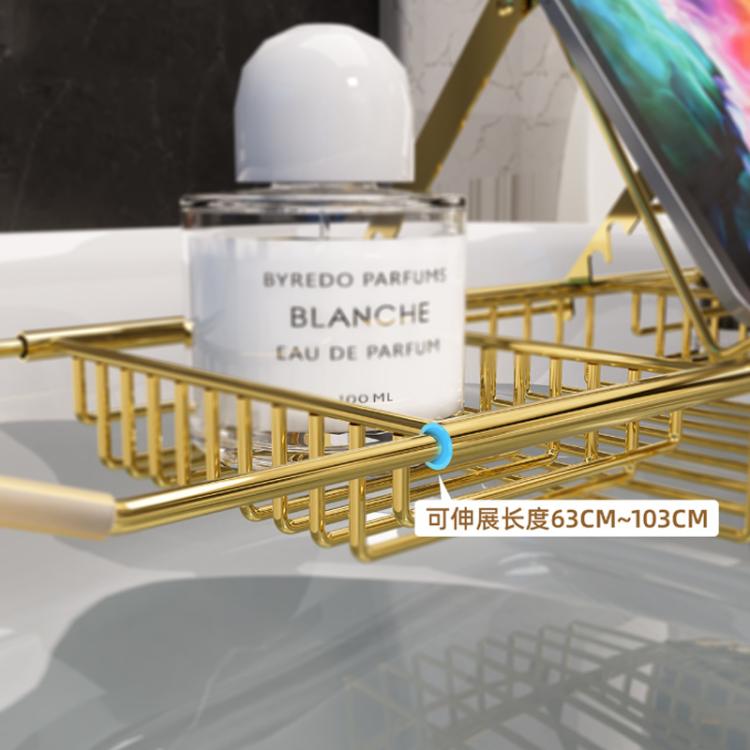 Gold stainless steel extendable bathtub caddy shelf holding toiletries and resting across tub