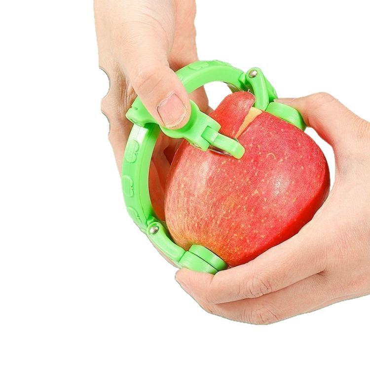 Green hand-crank peeler held in hands while peeling a red apple