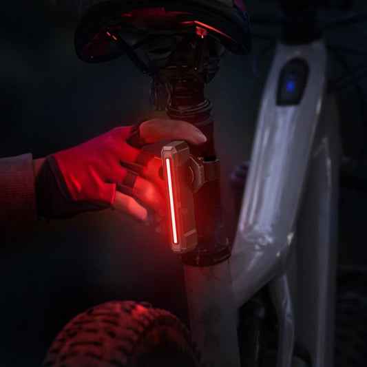 Bike taillight glowing red with a vertical light bar near the bicycle frame