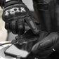 Black motorcycle gloves holding a smartphone with touchscreen-ready fingers