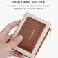 Brown compact zip card wallet held in hand, featuring a front card pocket.