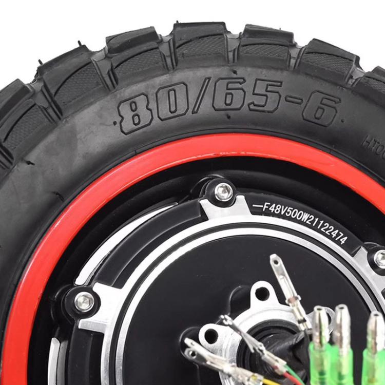 Close-up of off-road scooter tire and motor hub, black tread with red rim ring