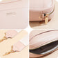 Pink crossbody pouch details: logo patch, key ring, and zippered opening.
