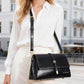 Black waxed leather small square crossbody bag worn with shoulder strap
