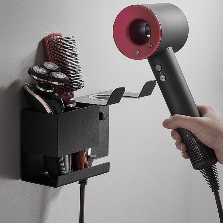 Hand installs black wall-mount hair dryer holder with divided tool storage.