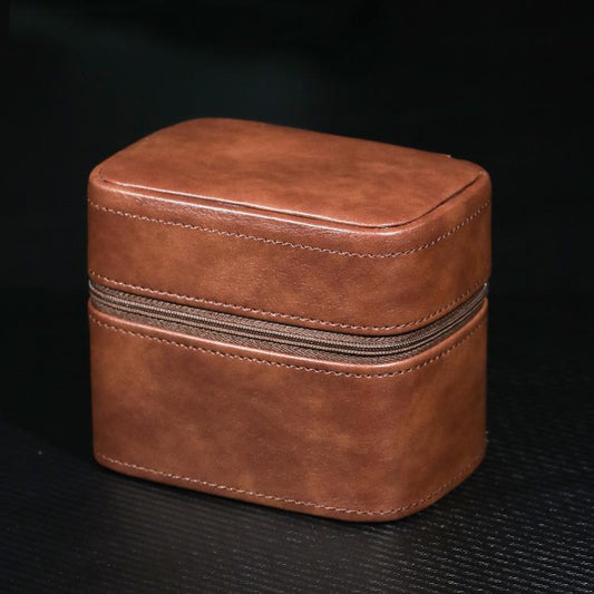 Brown leather watch storage pouch with zipper, rounded case shape and stitched edges.