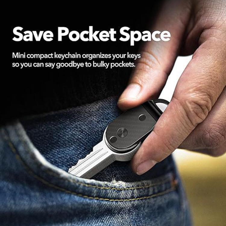 Hand holding a dark mini key holder clipped to jeans pocket keys