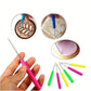 Clay sculpting tool set with pink and green detail needles, hand holding one tool