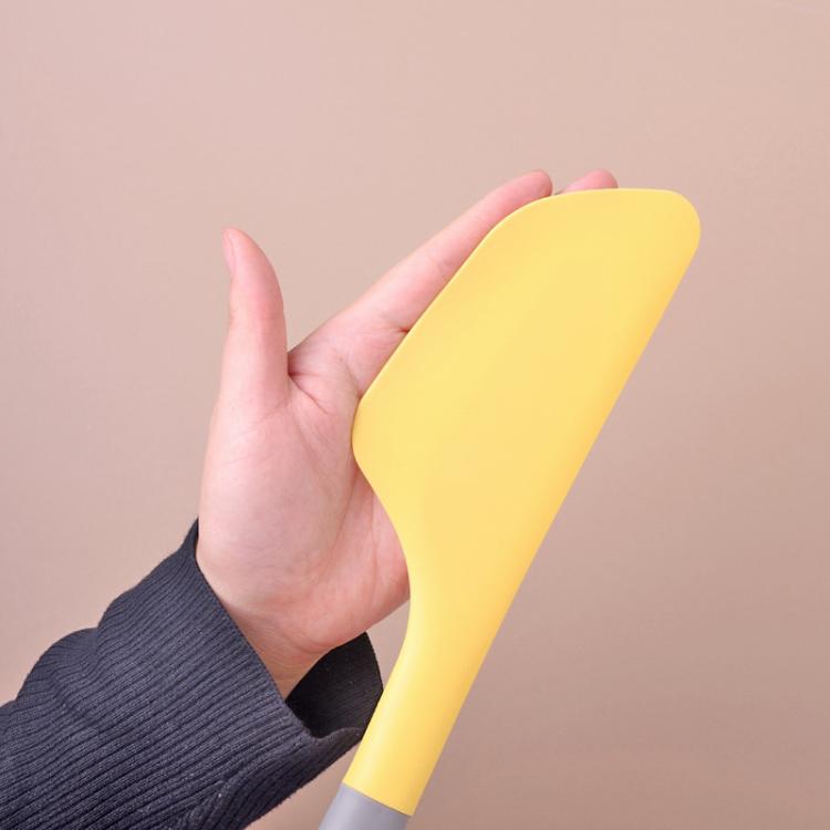 Yellow silicone spatula with grey handle and hanging hook hole, held by hand