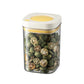 Vacuum food storage jar with yellow lid, clear body filled with green dried seeds