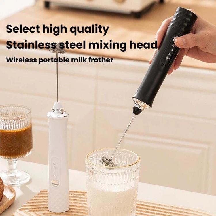 Black handheld milk frother being held with stainless mixing head and whisk rod