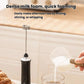 Black milk frother with balloon whisk attachment pouring into a cup