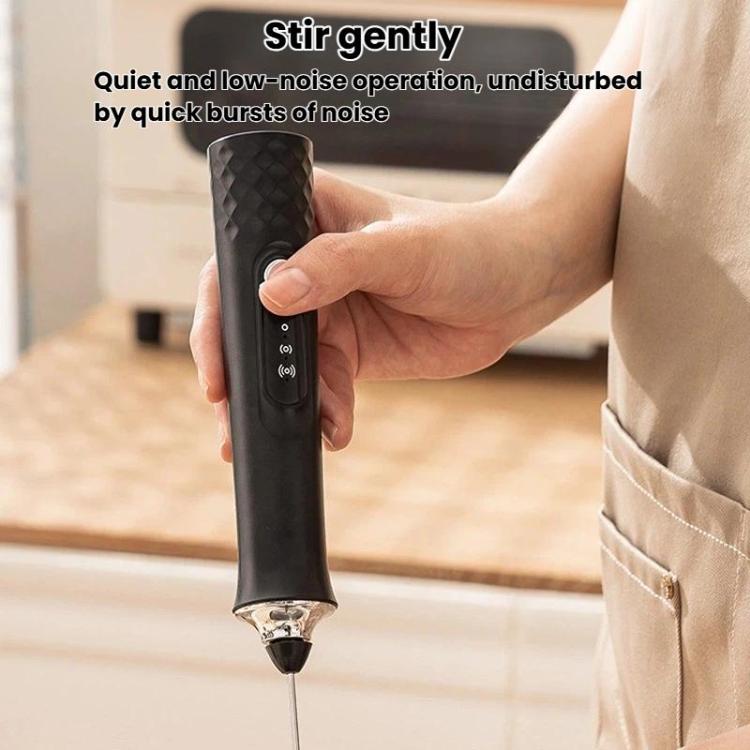 Black handheld electric milk frother held in hand with mixing whisk head