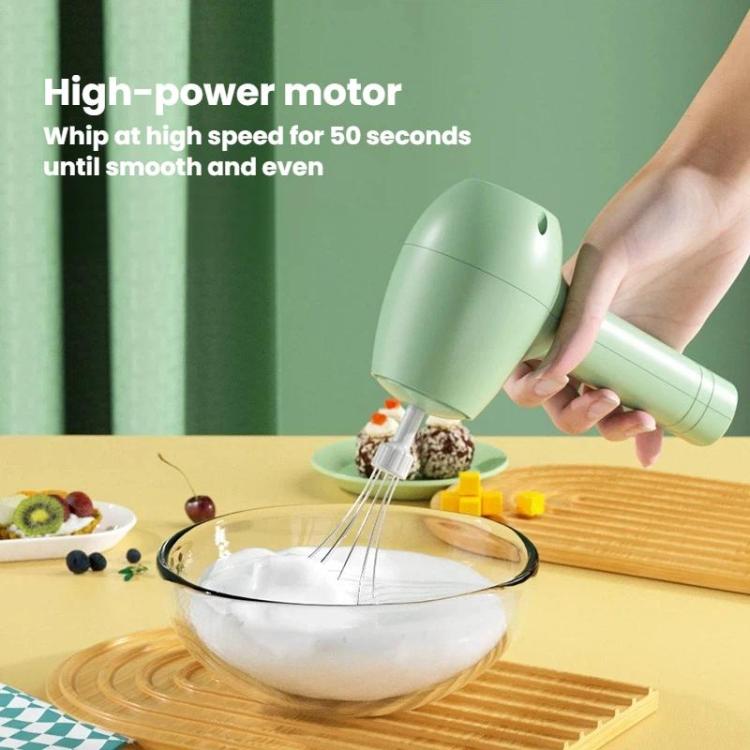 Green handheld electric milk frother whisking batter in a glass bowl