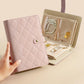 Lavender and beige jewelry organizer book opened with multiple padded compartments for jewelry.