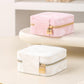 Pink and white travel jewelry organizer pouch with gold zipper and lock detail.
