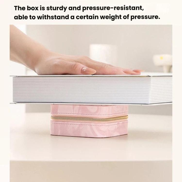 Pink travel jewelry organizer pouch on a shelf; hand lifts the lid beside the zipper.