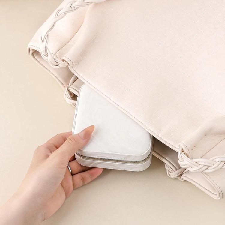 Light pink travel jewelry organizer pouch with drawstring closure and zipper edge.