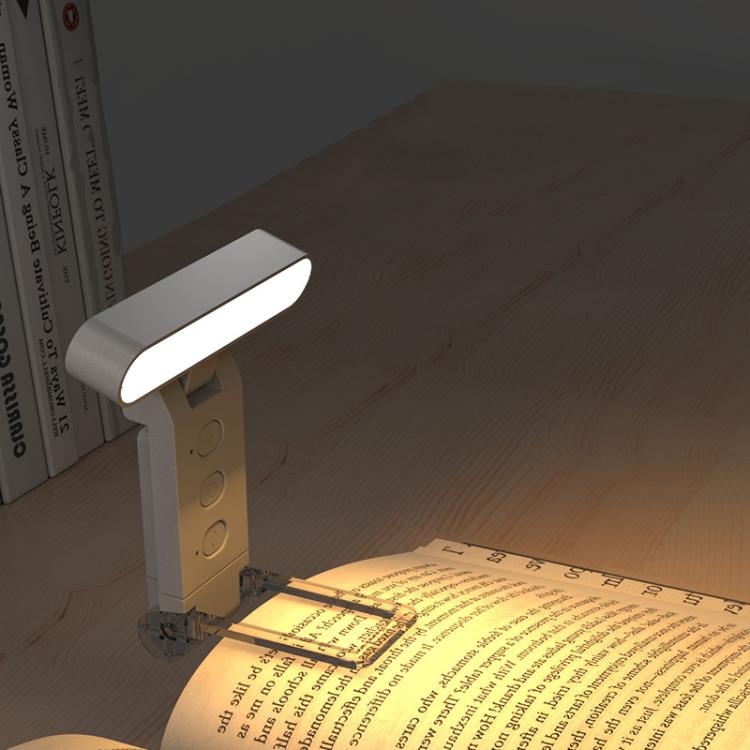 Lit clip reading lamp with LED folding bookmark clipped to open book on desk.