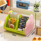 Green cosmetic storage rack with open front holds pens, tape, scissors, and a smartphone