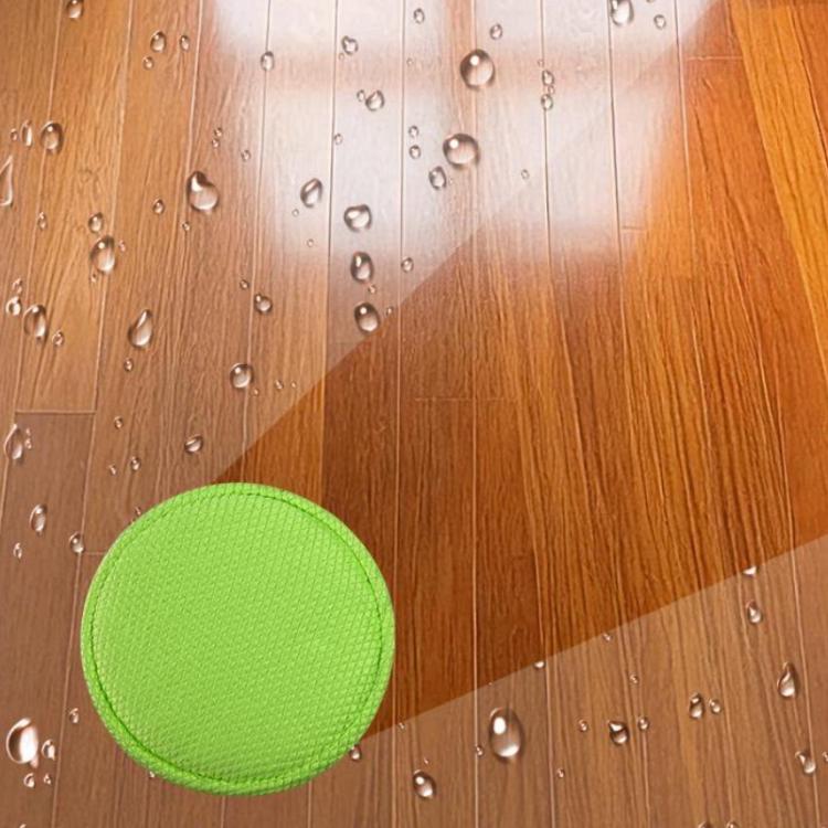 Round green waffle-weave robot mop pad on a wooden floor with water droplets.