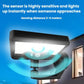 Solar motion sensor wall light glowing white with wide detection beam, black