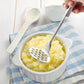 Stainless steel potato masher mashing potatoes in a white bowl