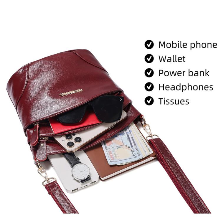 Red leather crossbody bag open to show mobile phone, wallet, and power bank inside
