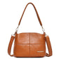 Light brown leather shoulder bag with top handles and crossbody strap, front logo patch