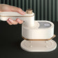 White handheld garment steamer being held above fabric on a base stand