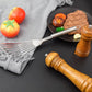 Stainless steel slotted spatula with angled fork head on a skillet