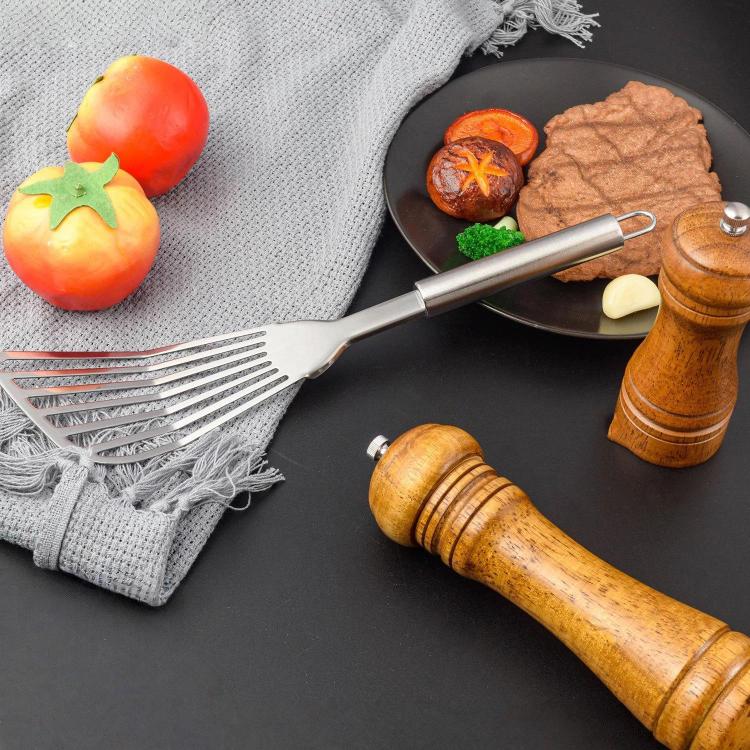 Stainless steel slotted spatula with angled fork head on a skillet