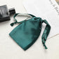 Teal satin drawstring pouch for small jewelry, with gathered top and ribbon ties.