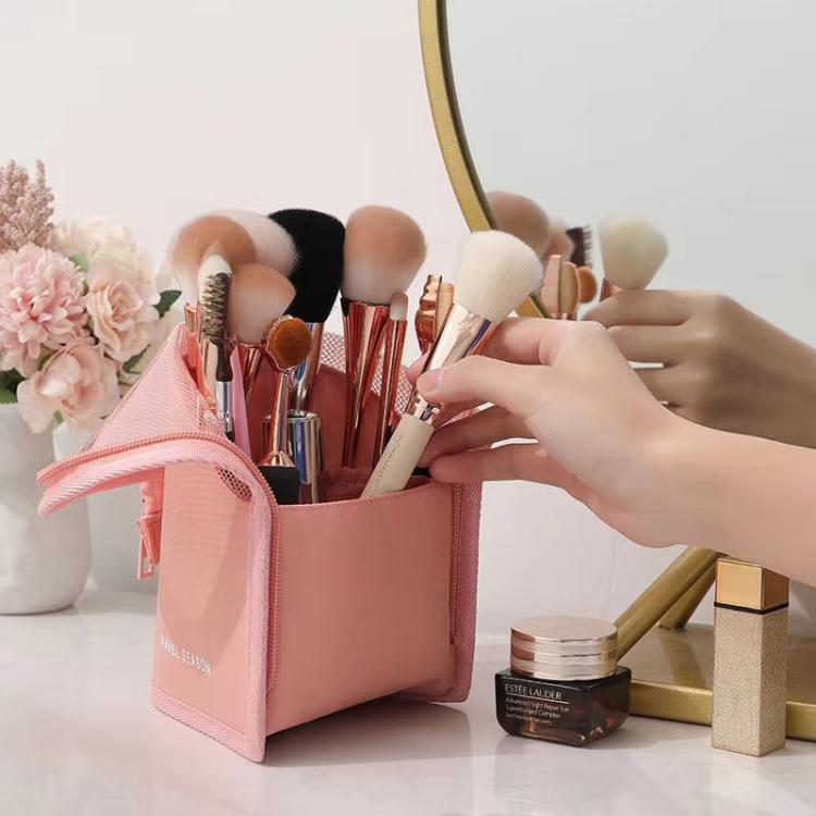 Pink mesh cosmetic bag open with brushes and makeup items inside