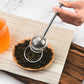 Hand holding round mesh stainless steel tea infuser strainer above tea leaves