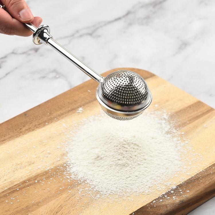 Stainless steel tea infuser sphere strainer over loose tea on a wooden board