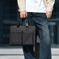 Men's waterproof laptop messenger bag in black carried in hand with front dual pockets