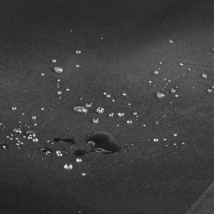 Close-up of dark gray waterproof fabric with water droplets beading on surface