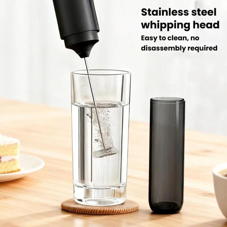 Black electric milk whisker inserting into glass cup with stainless whisks head
