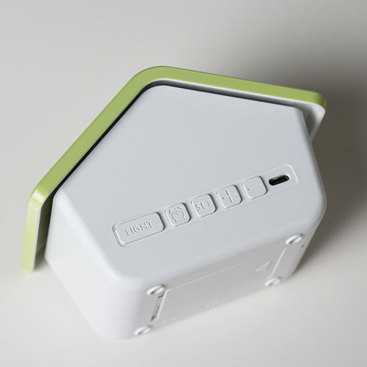 White house-shaped digital alarm clock side view with green roof and control buttons