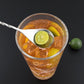 Stainless steel stirrer spoon with twisted handle above a drink glass