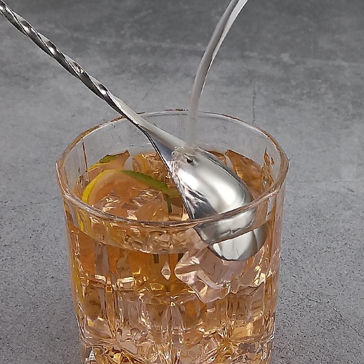 Polished stainless steel stirrer spoon with twisted handle in a drink glass