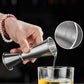 Stainless steel jigger measuring cup pouring stream into glass