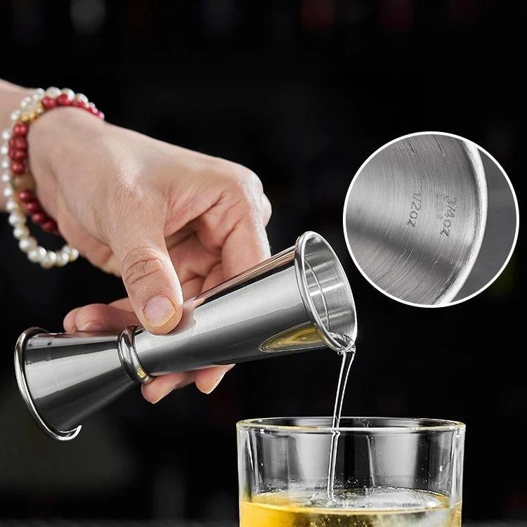 Stainless steel jigger measuring cup pouring stream into glass