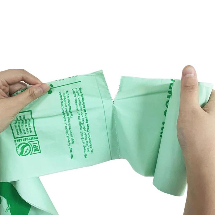 Compostable PLA garbage bags, light green flat bag held open by hands