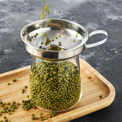 Stainless steel jam funnel with wide spout and side handle, holding green peas